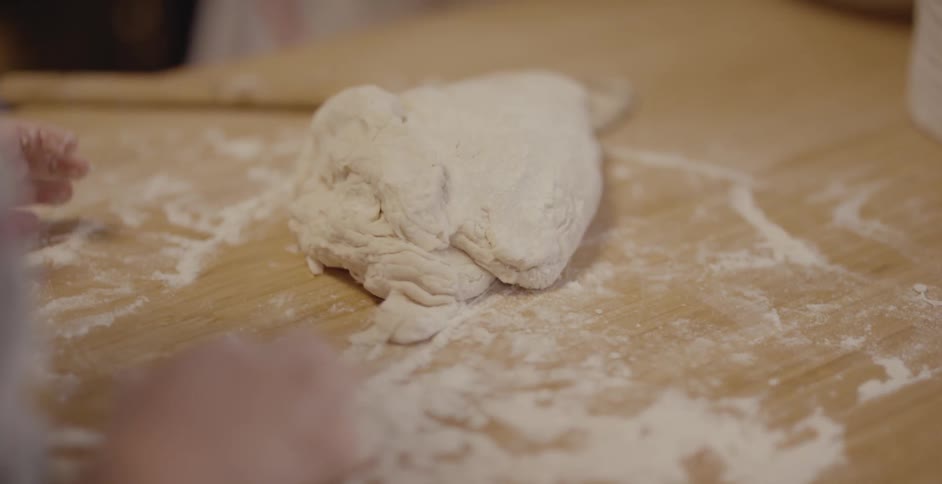 A man and young girl make dough in a kitchen