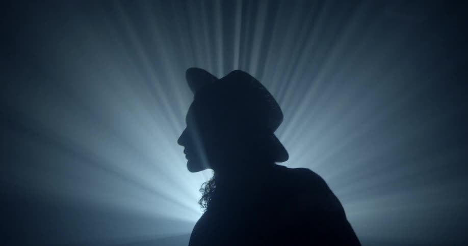 A person is dancing as a beam of light is projecting behind them