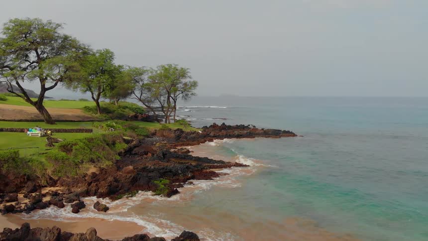 Water crashes to a rocky grassy shore