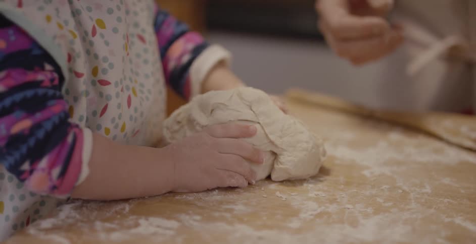 A child presses some dough on the cutting board