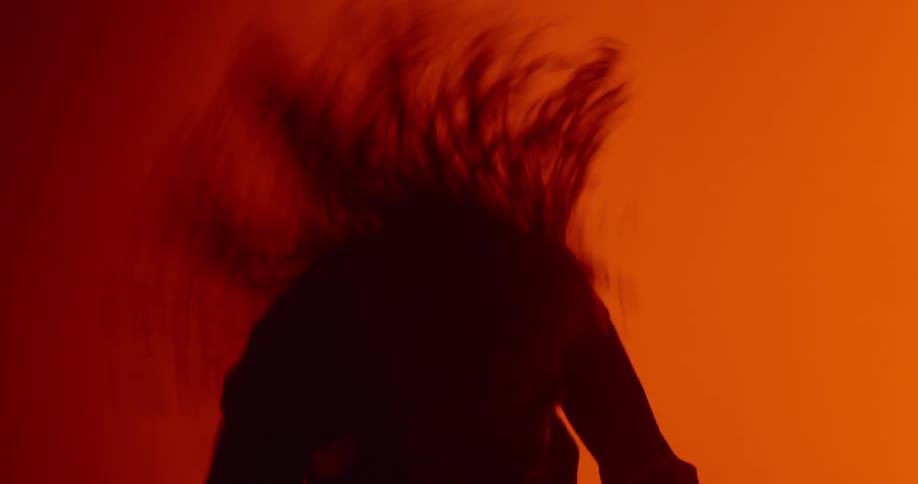 A man with long hair dances and whips his hair