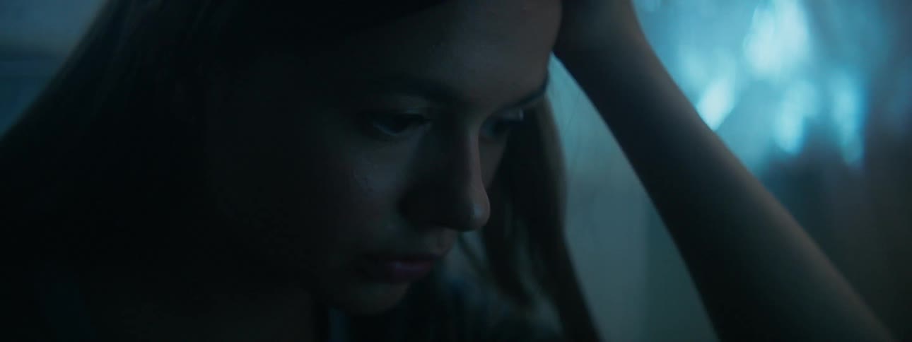 A girl is sitting deep in though inside at dusk
