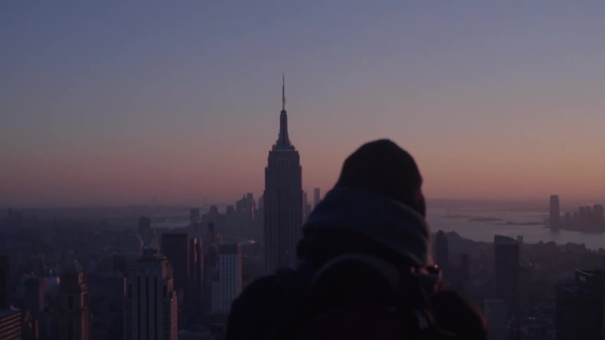 A man stands at a point high above and city and takes in views of downtown