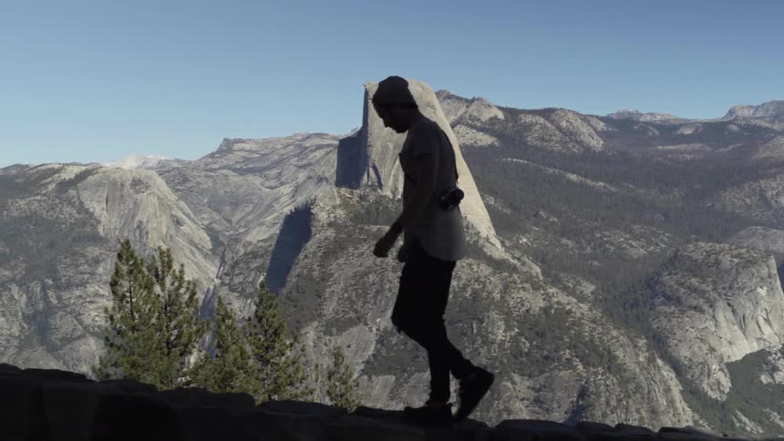 A man hikes in mountains with a camera