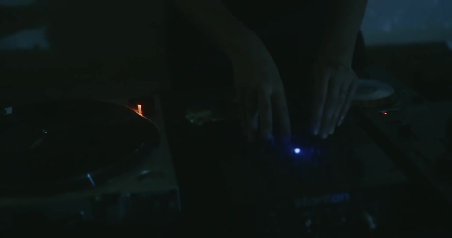 Person touches dj equipment with flashing lights around