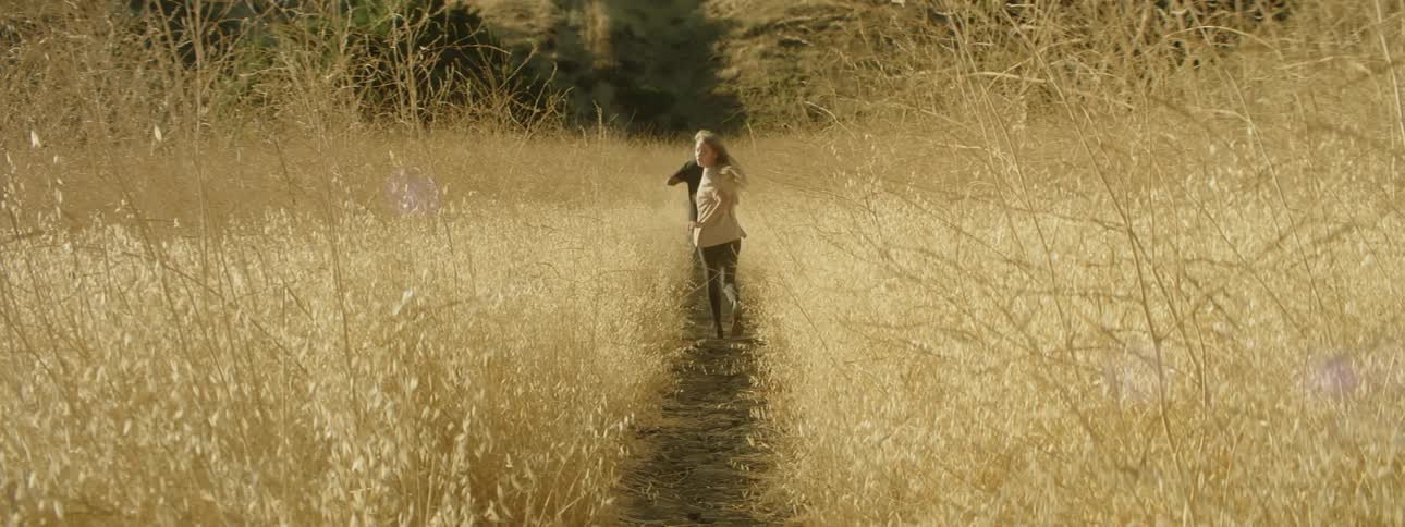 Man and woman run on a path through tall weeds