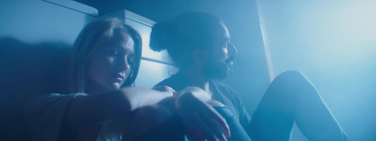 A man and woman sit in a dark laundry room