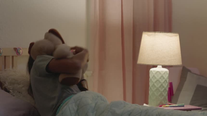 A girl snuggles with a stuffed animal in bed