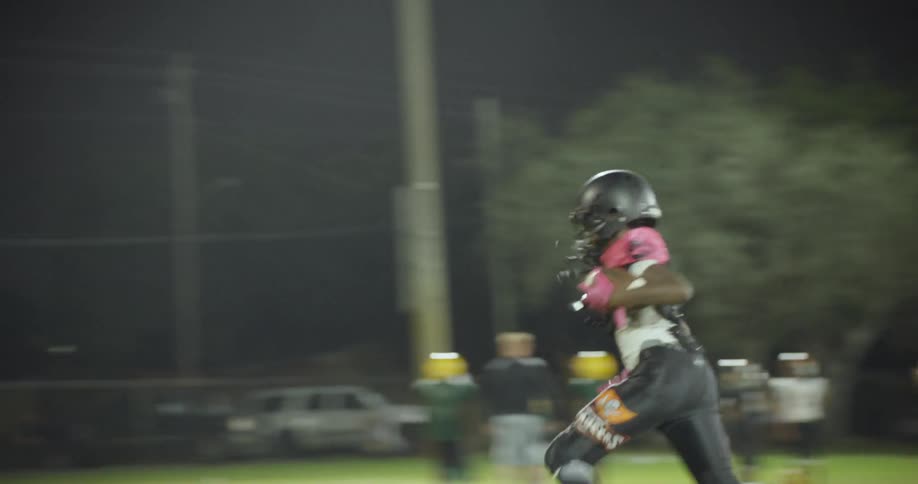 A high school football player catches a pass and runs