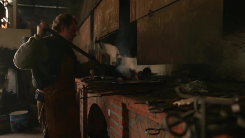 The man uses a shovel to put out a flame on the stove