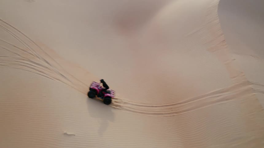 Four wheelers are driven over sand dunes