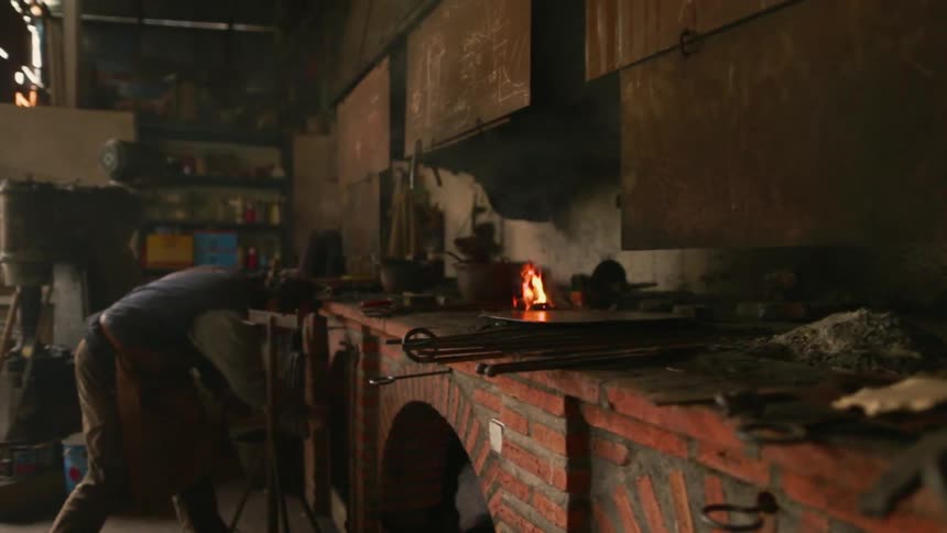 Man works in a workshop with a blazing fire