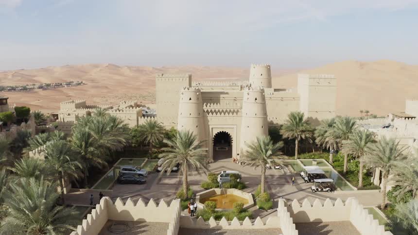 Bird flies over a large castle in the desert