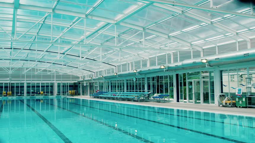 A large swimming pool in a room with a windowed roof