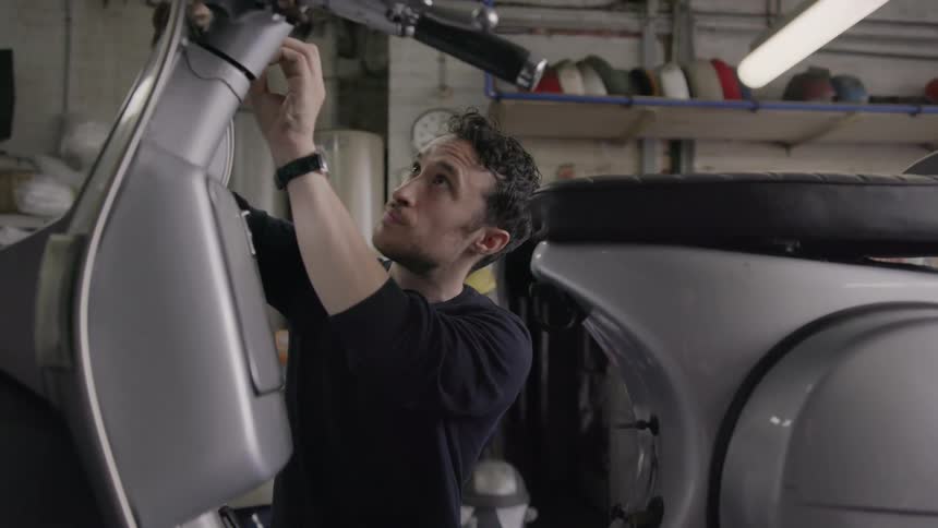 A mechanic works on a scooter