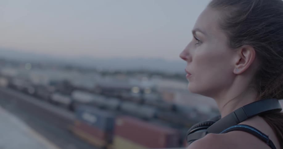 Woman wearing headphones looks out at the city