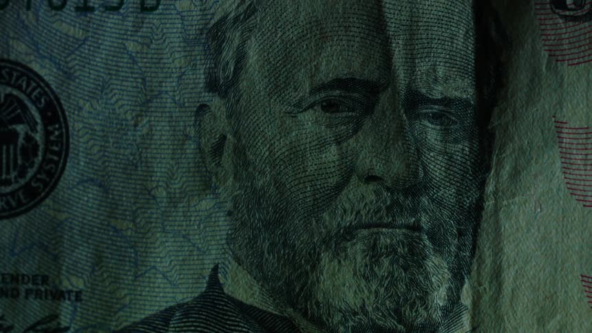 Light shines on the image of grant on a $50 bill