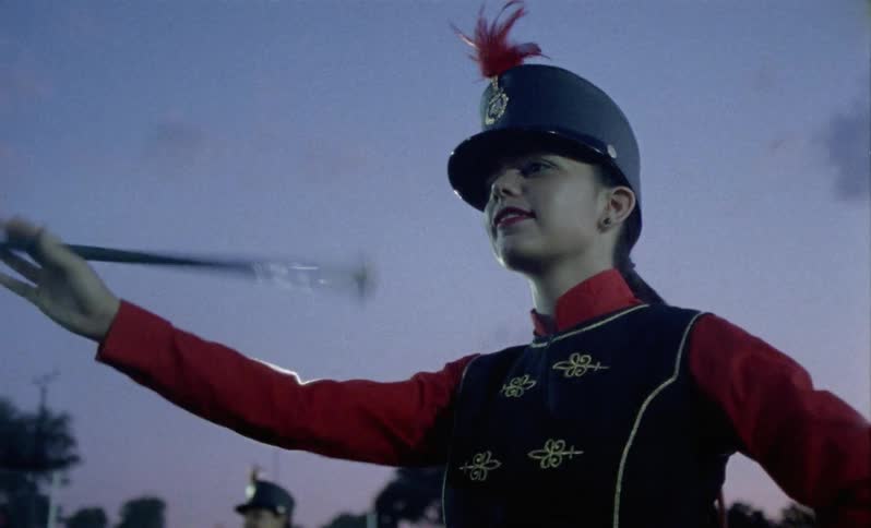Teenagers twirl batons in a field at night