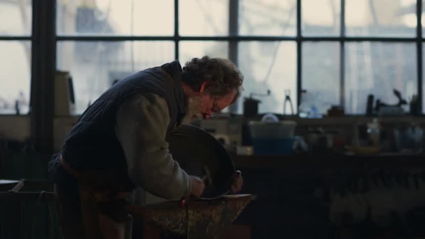 A man is hammering something in his shop