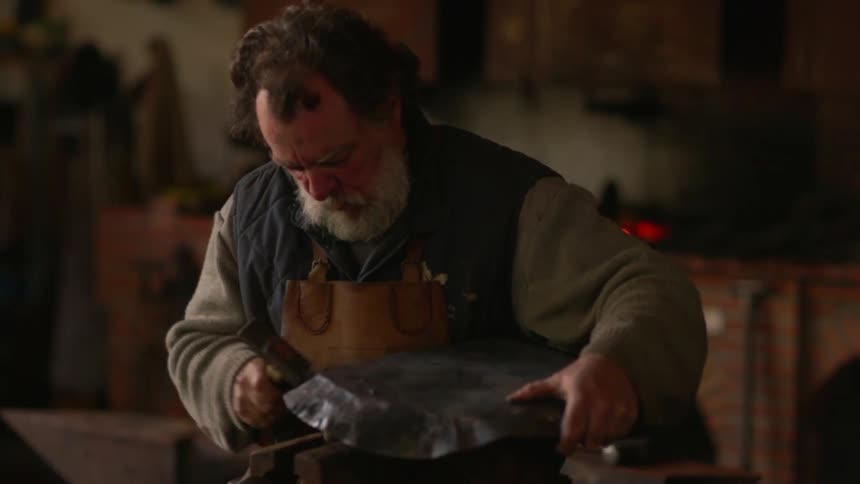 A blacksmith hammers a piece of metal