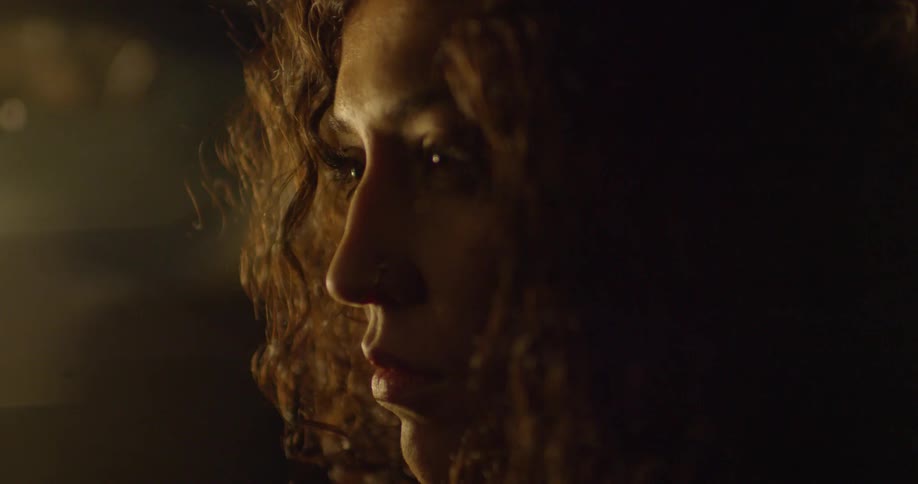 A woman with curly hair looks around the room