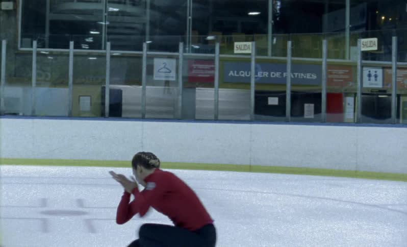 An ice-skater is spinning as she trains inside