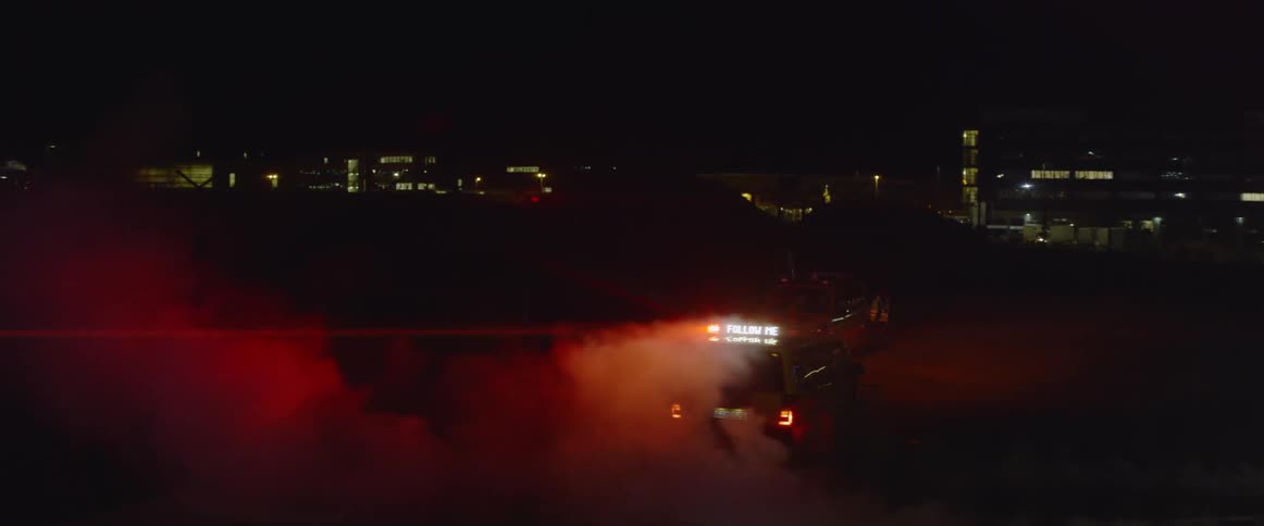 A vehicle with flashing lights drives at night