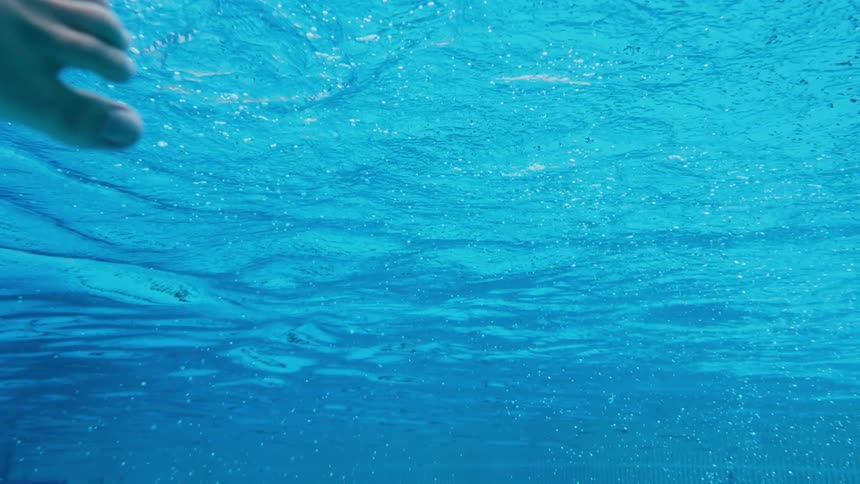 A person is gliding as they swim in a pool in daylight