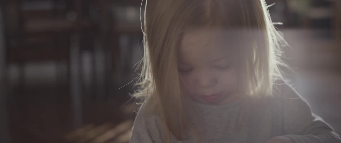 A little girl is concentrating on something ash she plays inside in daylight