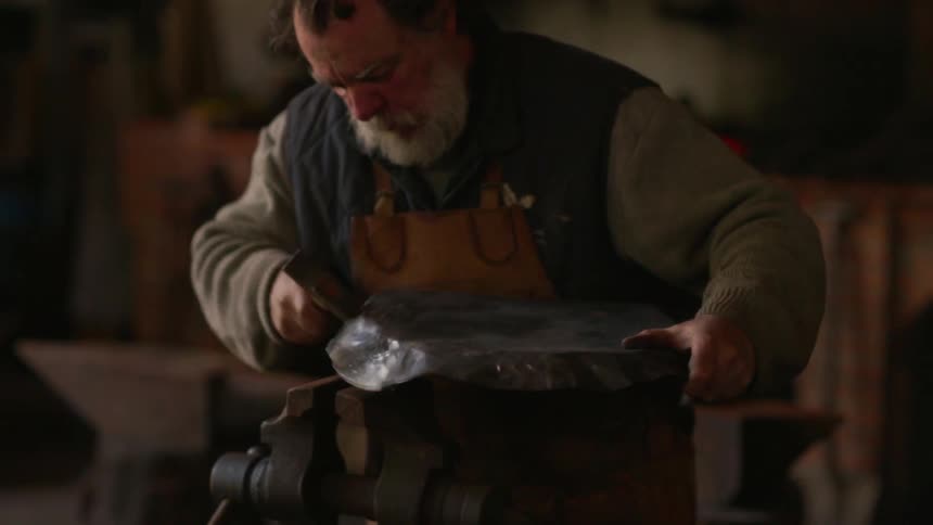 A blacksmith hammers a piece of metal