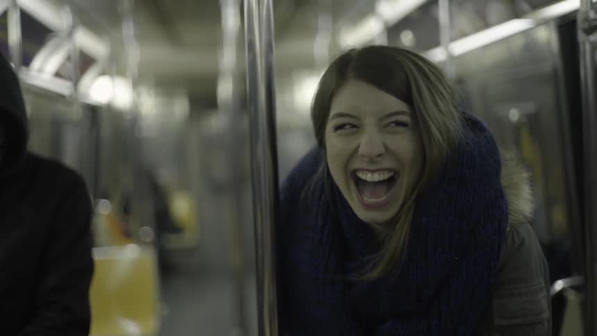 Woman laughing and twirling around a pole on the bus