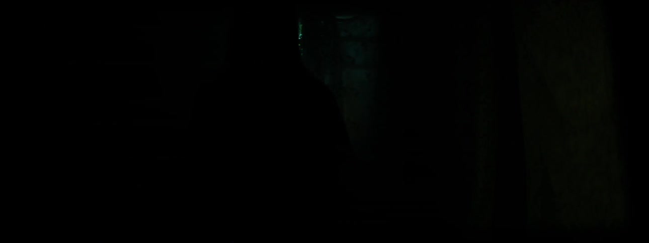 A woman stands in front of a window in a dark room