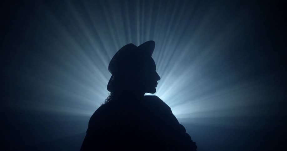 Bright lights shine behind a silhouetted person
