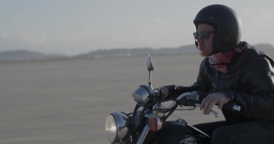 Man rides a motorcycle across a rural field