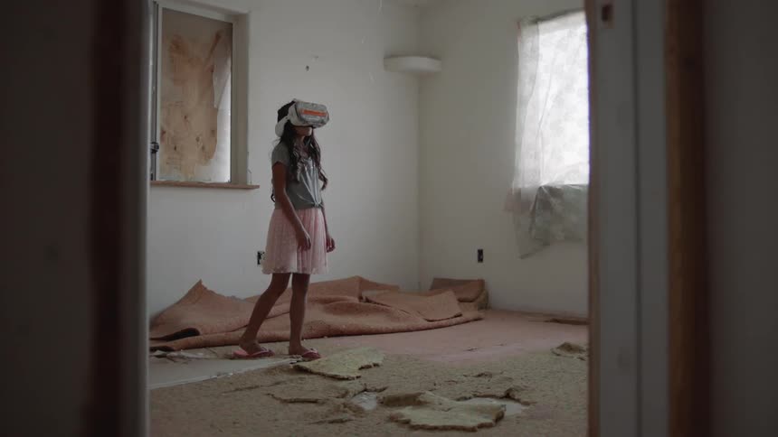 A girl stands in a room with virtual reality glasses on