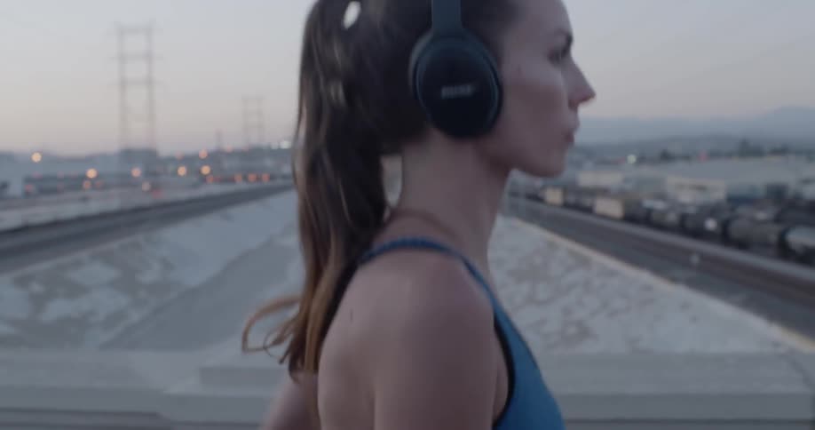 Woman wearing headphones jogs on a bridge