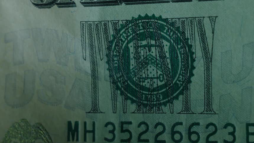 A light shines on a twenty dollar bill