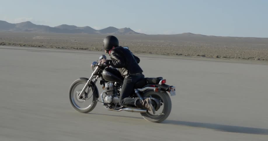 A motorcyclist rides across a desert