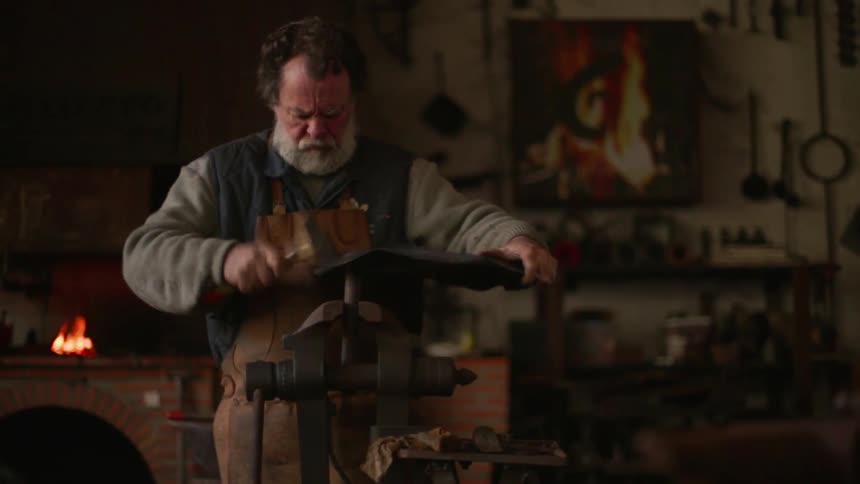 A blacksmith hammers a piece of metal