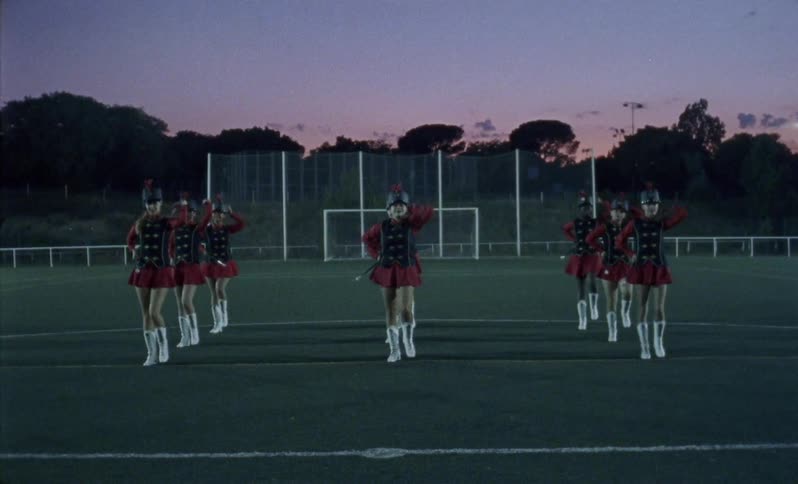 Teenagers twirl batons in a field at night