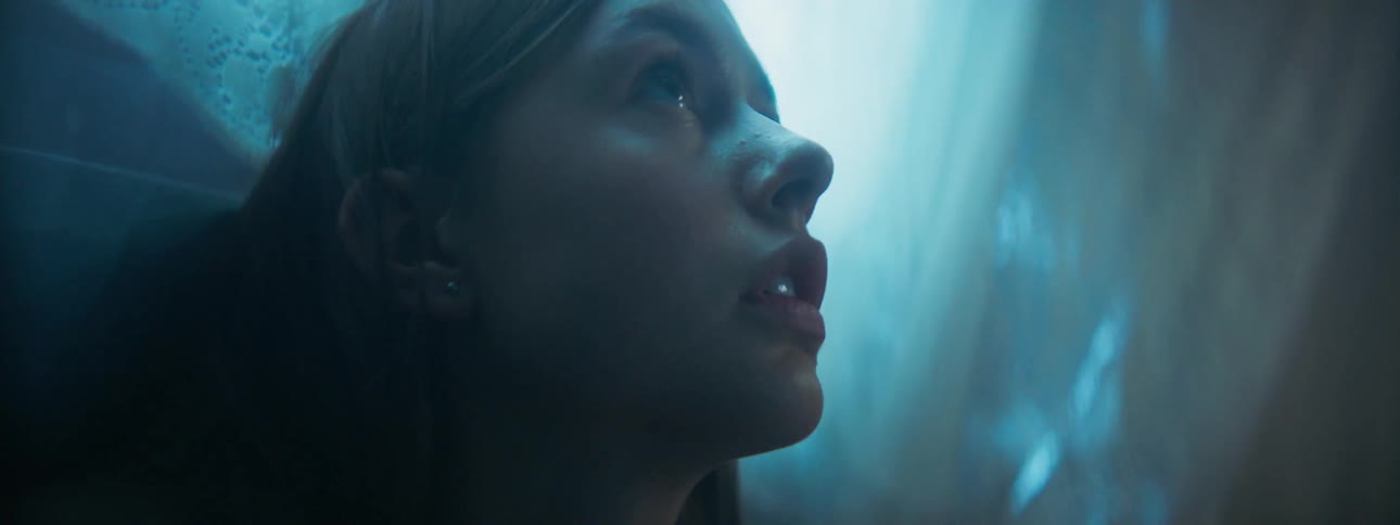 A woman looks up in a dark room
