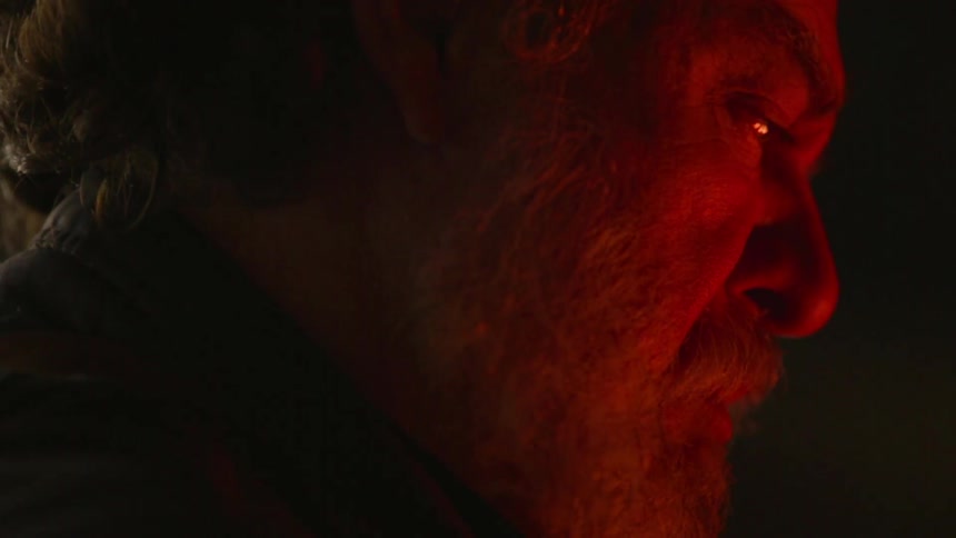 Man sits next to a fire at night