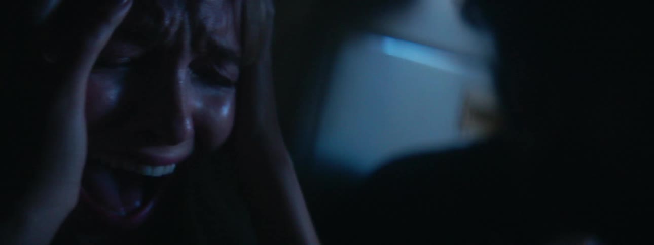 A woman holds her head and screams