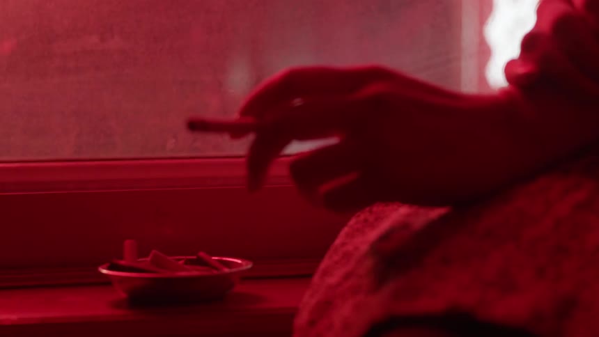A person smokes by the window