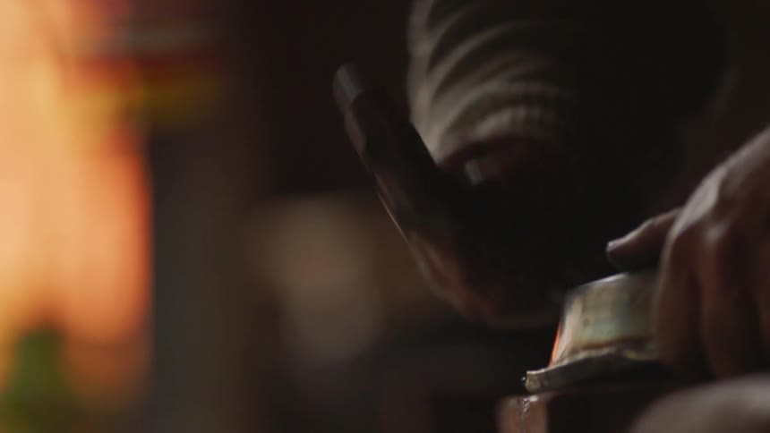 Man taps a piece of metal with a small hammer