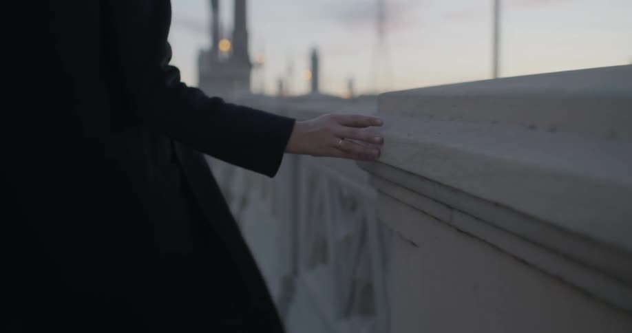 A woman rubs her hand along a stone wall