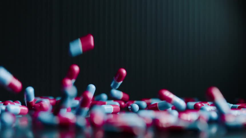 Red and blue colored pills are falling onto surface