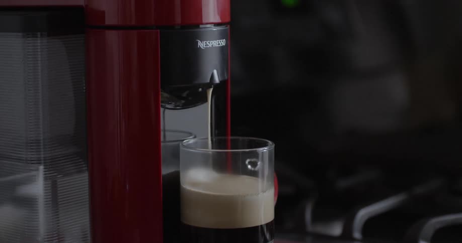 Coffee pours into a glass from a nespresso machine