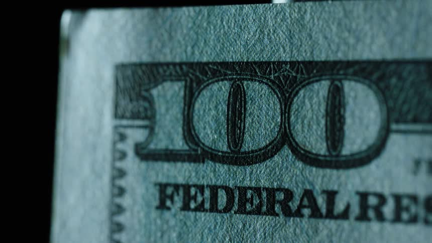 Light shines on and off of the corner of a 100 dollar bill