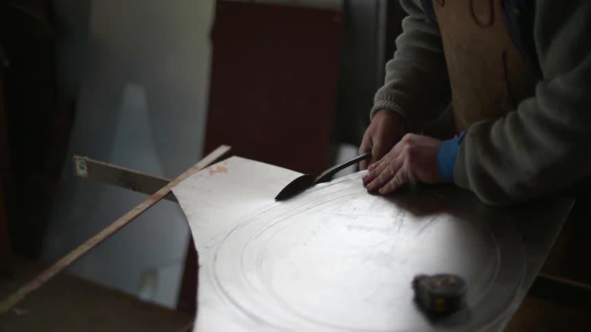 A blacksmith cuts a sheet of metal